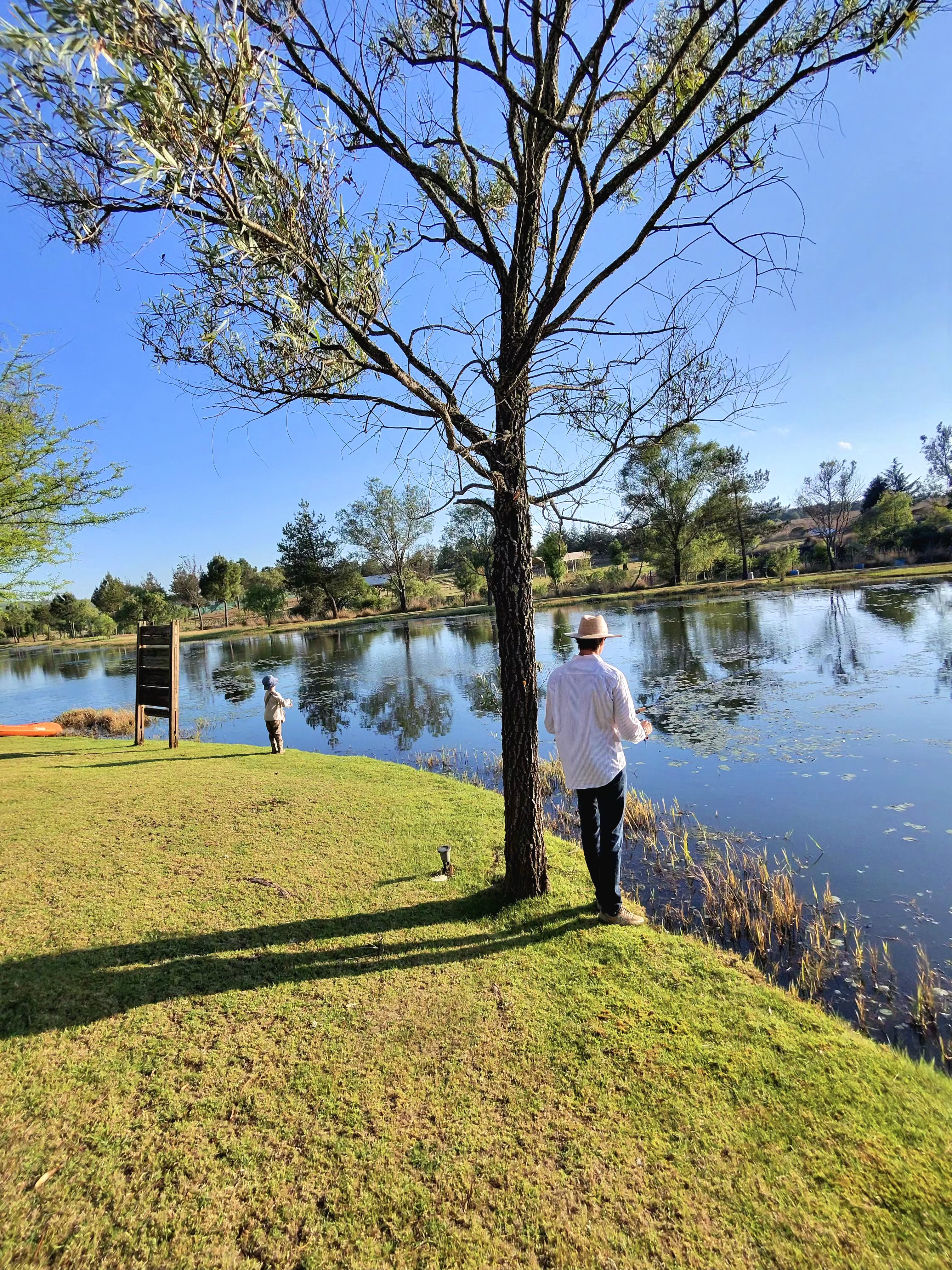 Padre e hijo pescando junto al lago en Los Reflejos
